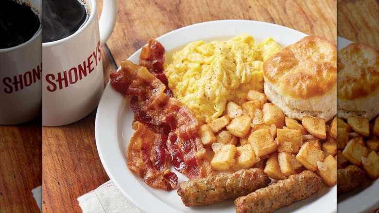 A plate of Shoney's breakfast food sits next to a Shoney's mug full of coffee