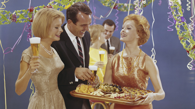 A host serving appetizers at a 1950s party