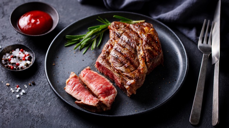 Sliced steak on a plate with condiments and cutlery