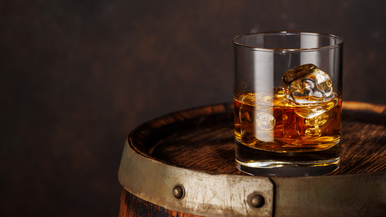 glass filled with whiskey on barrel