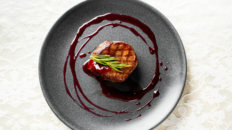 Top view of a filet mignon garnished with herbs.