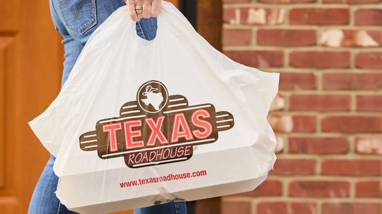 Someone carries a take-out bag from Texas Roadhouse.