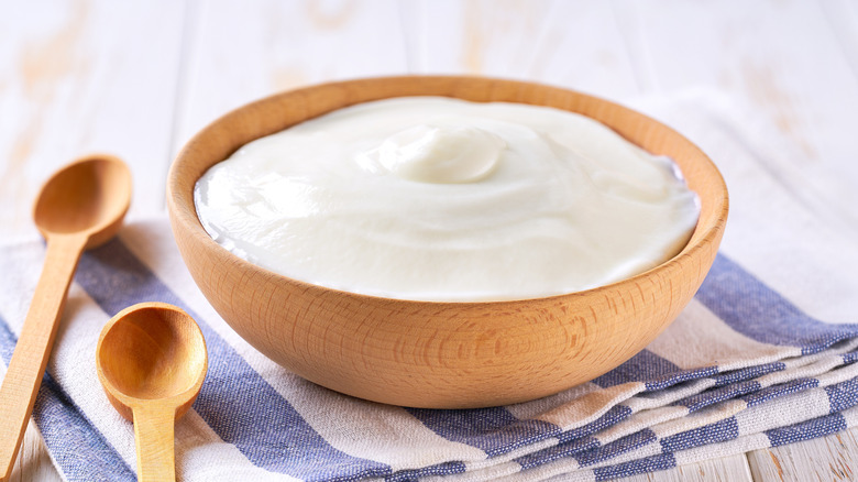 A wooden bowl of Greek yogurt on a towel.