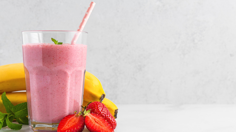 A glass filled with a strawberry banana smoothie and pink polka dot straw