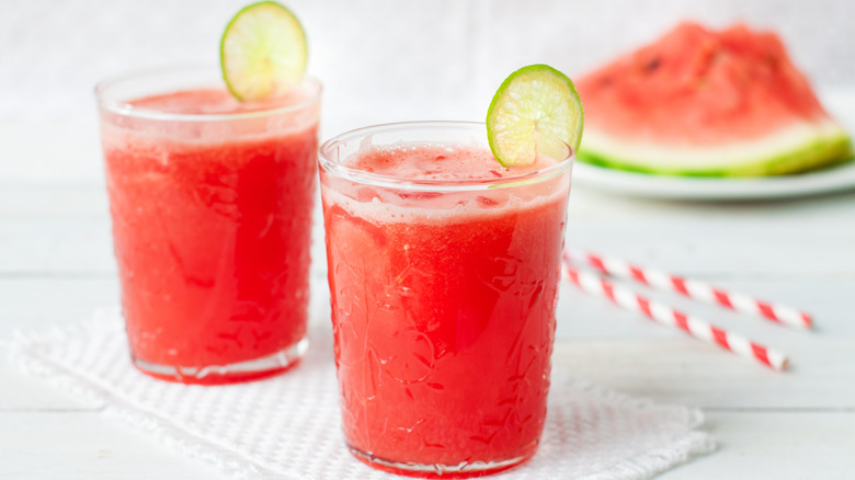 Two glasses of watermelon limeade garnished with lime slices