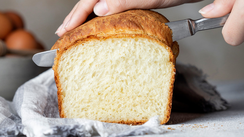 hand cutting fluffy loaf of bread