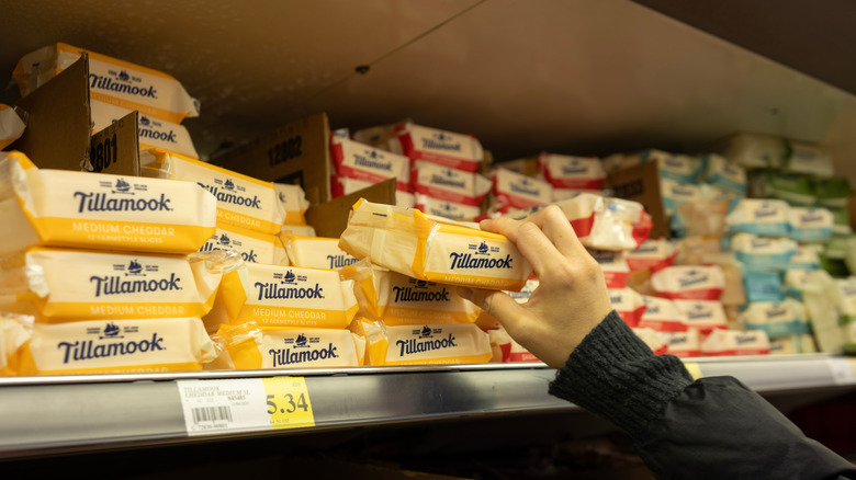 A customer reaches for a package of Tillamook cheese in a supermarket