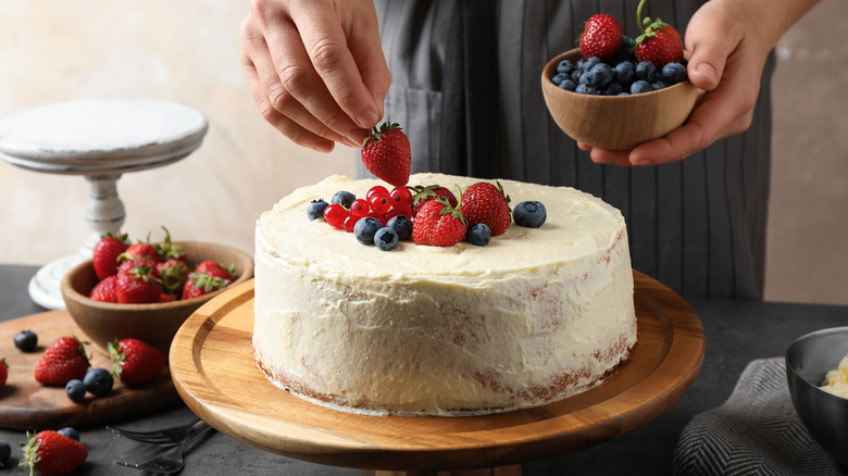 Decorating a homemade frosted cake with berries