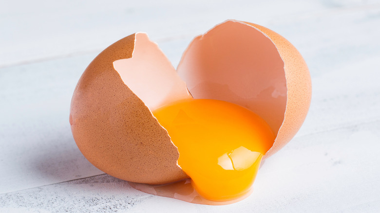 A brown egg cracked down the middle to reveal a yolk