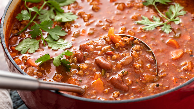 Large pot of chili with a ladle scooping some out.