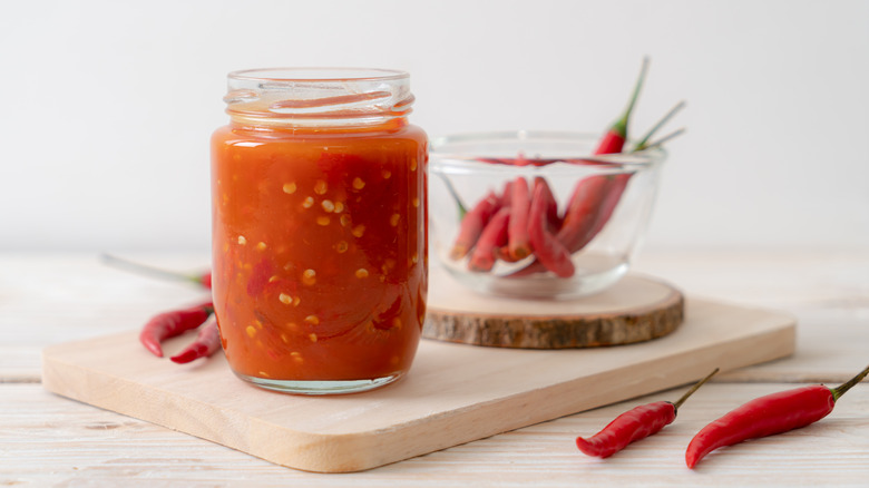 Sweet chili sauce in glass jar on cutting board