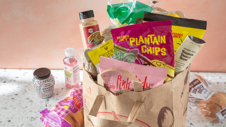 A Trader Joe's shopping bag is filled with Trader Joe's branded snacks and food items