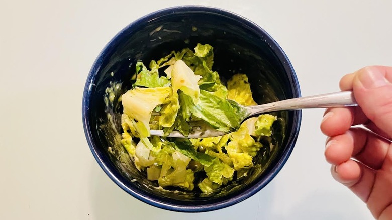 Fork holding up bite of salad with dressing