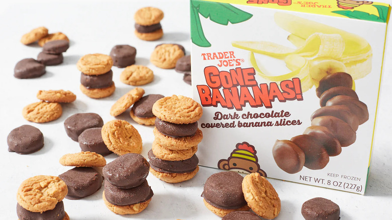 A box of Trader Joe's Gone Bananas! frozen treats sits next to individual chocolate-covered bananas slices stacked up with bite-sized cookies.