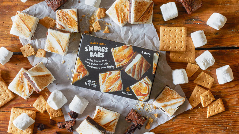 A box of Trader Joe's S'Mores Bars is surrounded by open S'Mores Bars, graham crackers, and marshmallows.