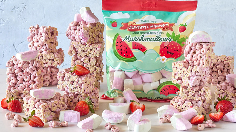 A bag of Trader Joe's Strawberry & Watermelon Marshmallows surrounded by marshmallows, strawberries, and cereal treats made using the marshmallows.