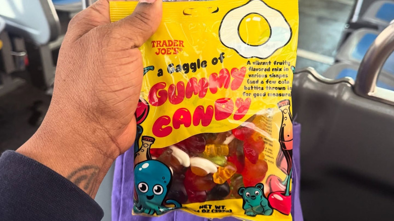 A hand holds up a bag of Trader Joe's gummy candy