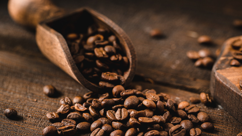 Coffee beans cascading out of a wooden scoop