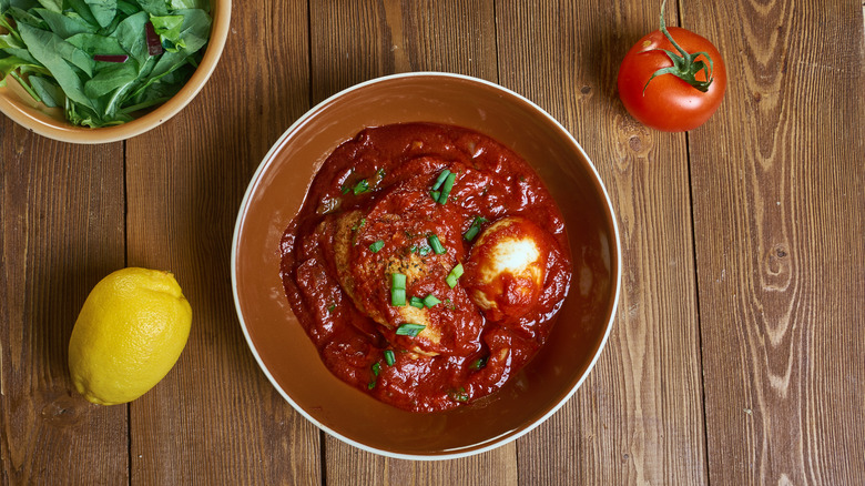 Doro wat, a spicy chicken stew, sits in a ceramic bowl with a hard boiled egg