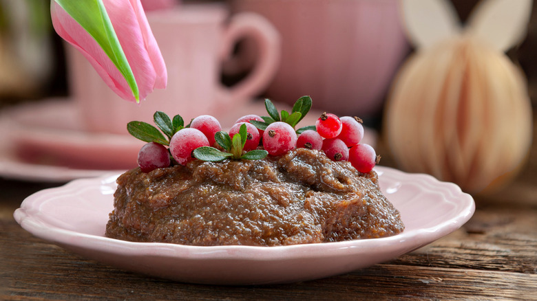 A Finnish rye pudding decorated with berries sits in a pink saucer