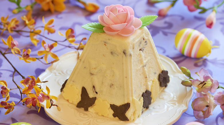 A traditional molded cheesecake called Pashka is decorated with a pink rose and chocolate symbols