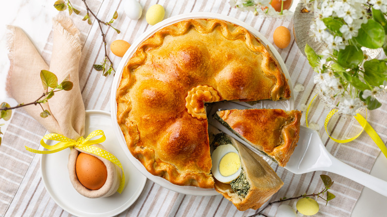Torta pascualina, a rustic pie with hard boiled eggs, spinach, and ricotta, sits on a white plate