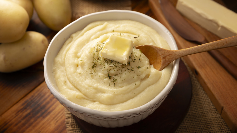 A bowl of mashed potatoes with a pat of butter on top