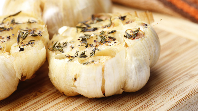 Bulbs of roasted garlic with herbs on a board