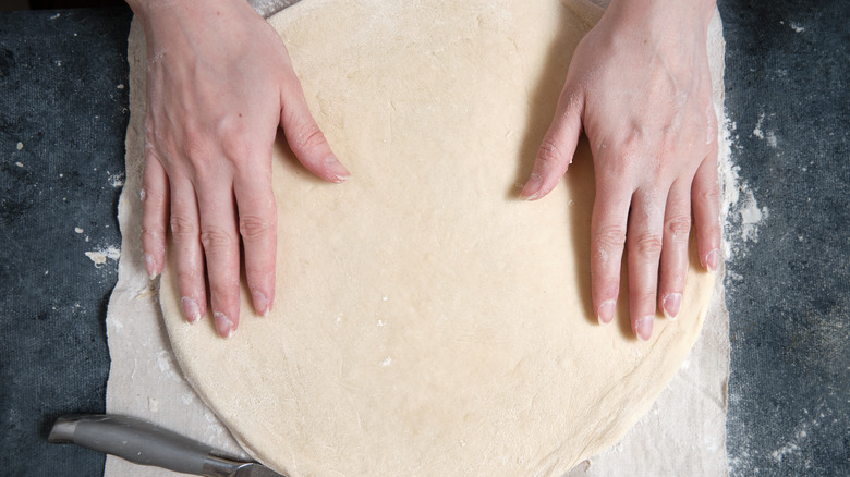 pressing out homemade pizza crust