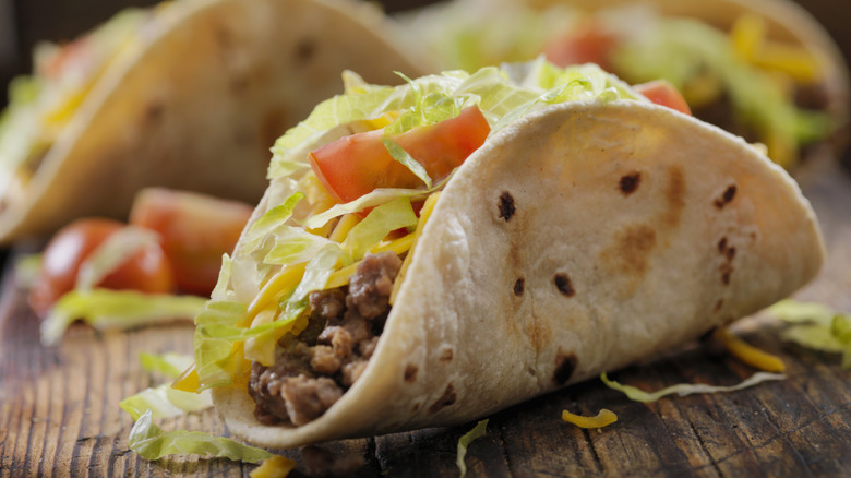 Ground beef taco in a soft shell tortilla on a wooden surface