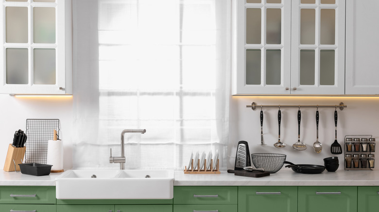 A bright kitchen with white and green cabinets