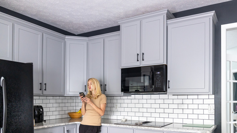 A homeowner reclines in a kitchen with white cabinets and grey walls
