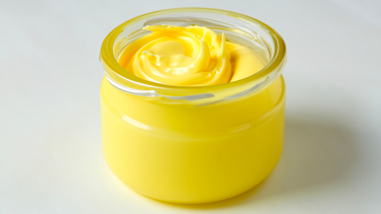 A glass jar full of yellow-colored beef tallow against a white background