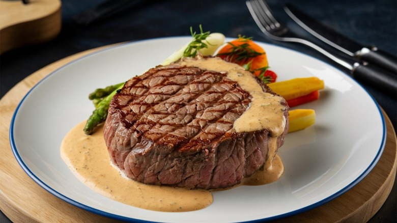 A chateaubriand steak with bearnaise sauce and a vegetable medley rest on a plate