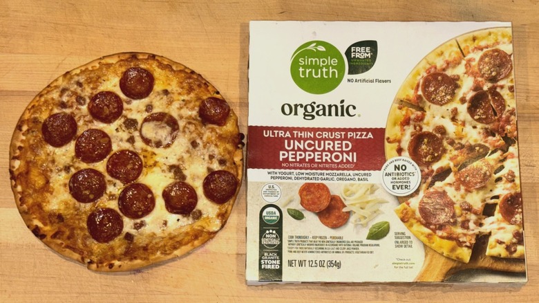 Simple Truth Organic Ultra Thin Crust Uncured Pepperoni Pizza baked and placed on a wooden cutting board next to the box