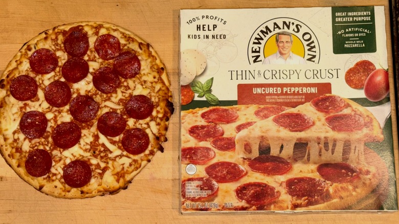 Newman's Own Thin & Crispy Crust Pepperoni Pizza baked and placed on a wooden cutting board next to the box