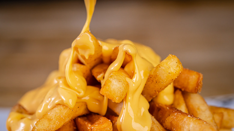 Cheese sauce being drizzled on fries