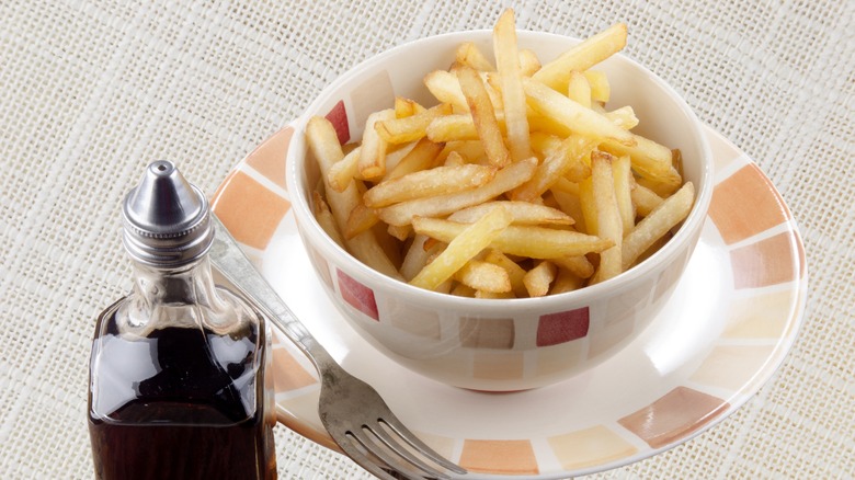 Bowl of fries with bottle of malt vinegar