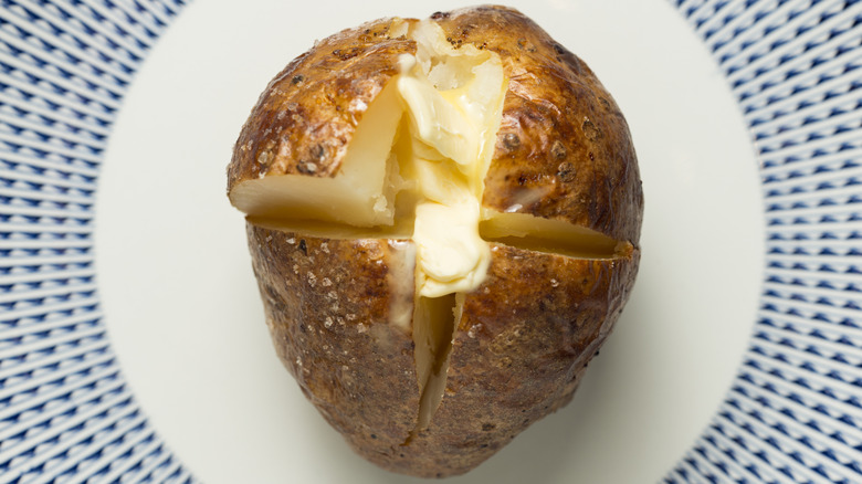 A baked potato with melted butter.