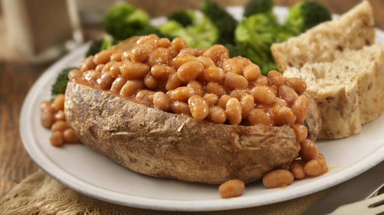 A baked potato topped with baked beans.