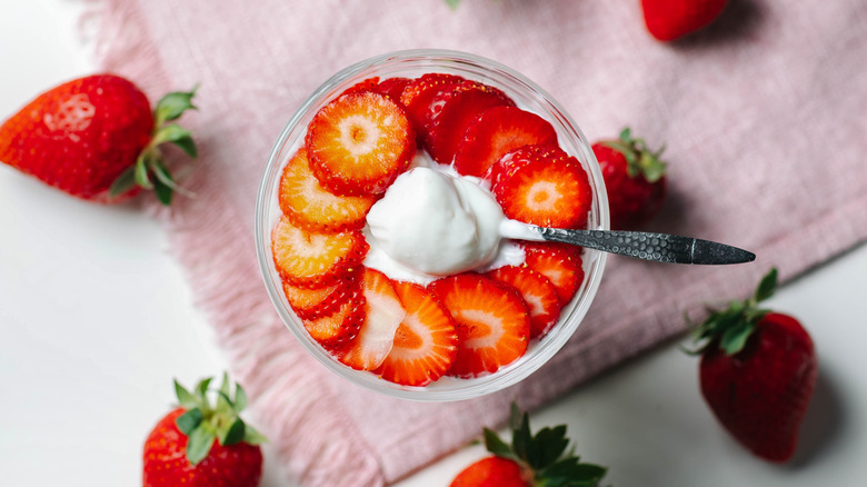 Glass of Greek yogurt topped with sliced strawberries