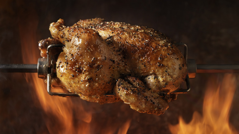 rotisserie chicken being cooked over fire