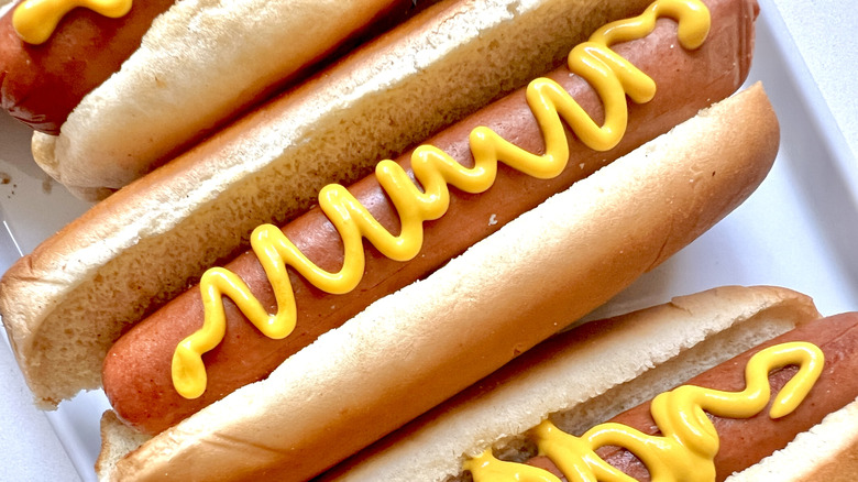 Hot dogs with mustard on white plate