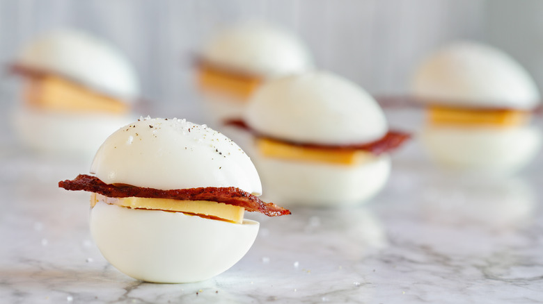 Boiled eggs used as sandwich buns stuffed with bacon and cheese