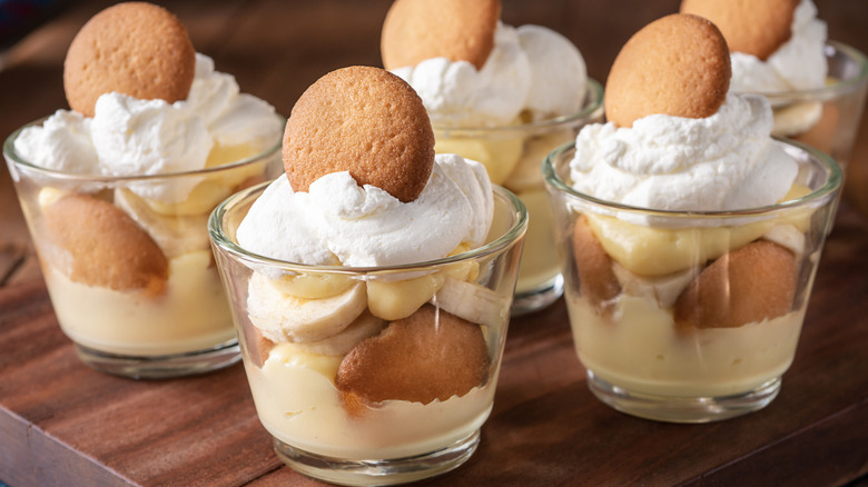 Banana pudding in individual cups on a wooden board.