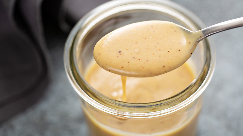 spoonful of aioli above a jar