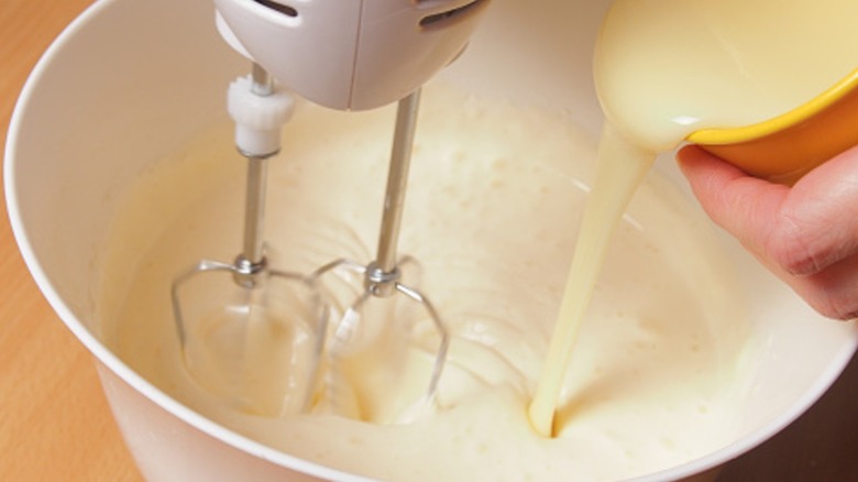 Adding sweetened condensed milk to cake batter.