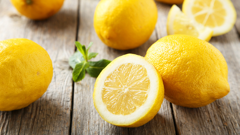 whole lemons and halved lemon on wooden table