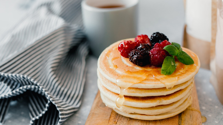 stack of pancakes with butter, berries, and syrup