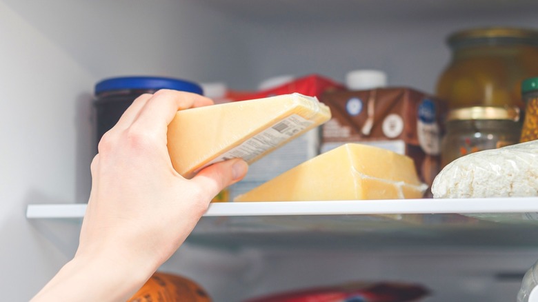 Hand taking cheese out of fridge